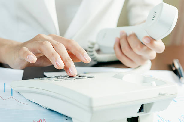 Dialling on a telephone Woman dialling on a telephone in an office dialling phone stock pictures, royalty-free photos & images
