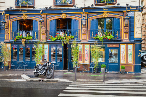 Paris, France - August 7, 2014: Black motorcycle stands parked near blue bar facade on the Quai Des Grands Augustins