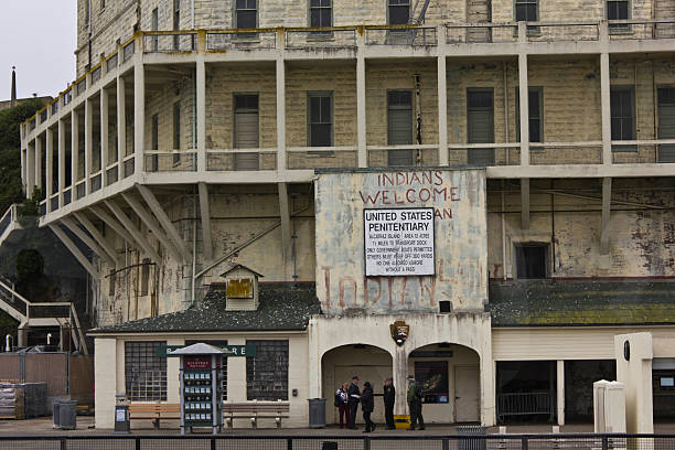 San Francisco, USa - August 12, 2013: Arriving in Alcatraz Penitentiary. External view of the building in a dull day in the summer season. Entrance sign detail with an old graffiti and people around
