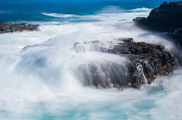 Photo of Raging sea flows over lave rocks on shore line