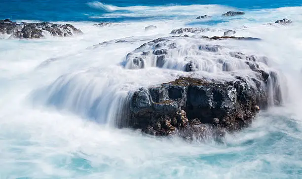 Photo of Raging sea flows over lave rocks on shore line