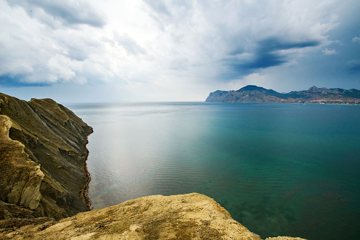 A landscape on sea. The yellow rock, azure water and cloudy sky.