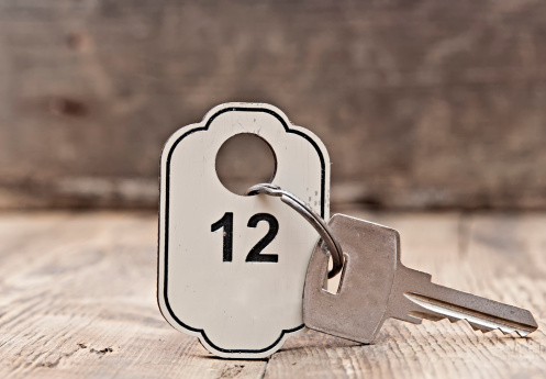 Hotel suite key with room number 12 on wood table
