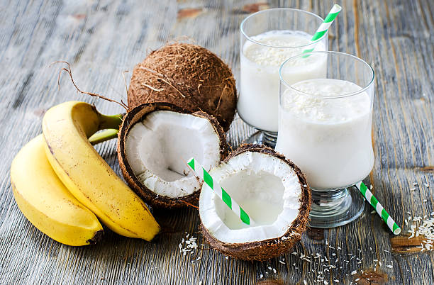 smoothie verre de lait de coco et de bananes sur fond en bois - smoothie banana smoothie milk shake banana photos et images de collection
