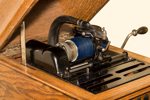 Close up of antique tabletop cylinder phonograph mechanism with blue celluloid cylinder.  Vintage technology circa 1920.  Lots of texture and history.  This is what provided entertainment in the days before homes and farms had electricity.