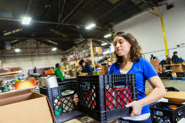 Young woman volunteering to organize donations in large food bank Young woman volunteering to organize donations in large food bank humanitarian aid stock pictures, royalty-free photos & images