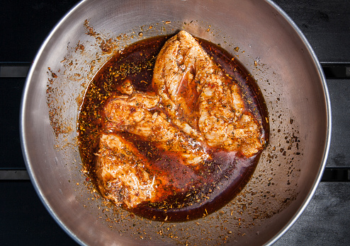 A bowl of chicken breasts marinating