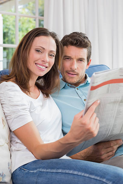 istock Relaxed young couple reading newspaper on couch 466616470