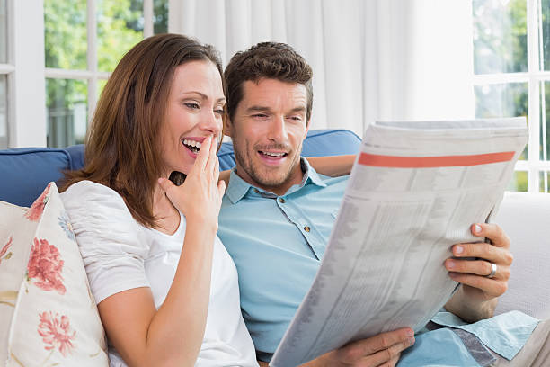 istock Happy couple reading newspaper on couch 466616484