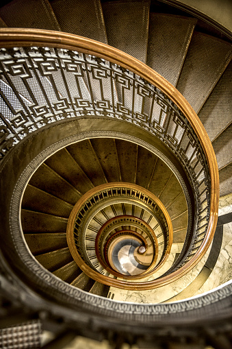 Natural light adorns a old-fashioned conical shaped spiral staircase in a historic old San Francisco building.