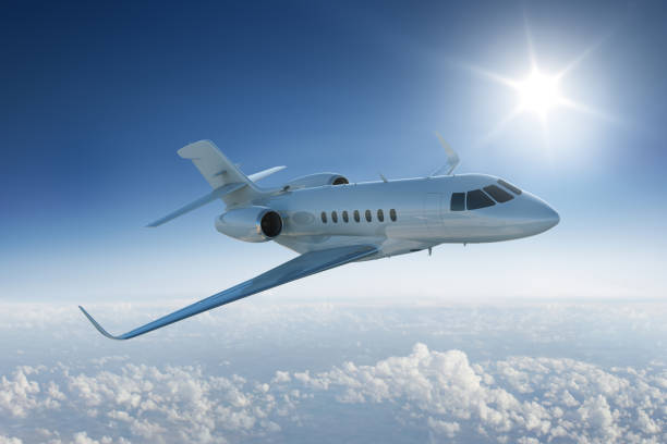 istock Private jet flying past sun in blue sky 466619660