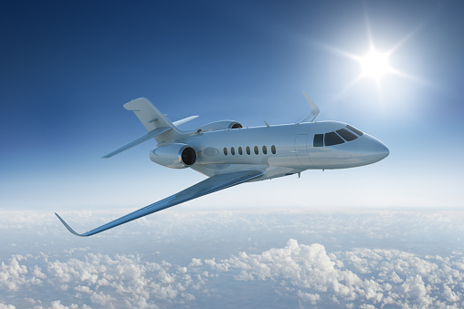 Private jet flying past sun in blue sky