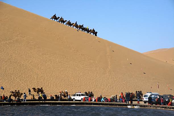 Camel riding on the huge sand dunes surrounding Badain lake in Badain Jaran desert. This desert is home to some of the tallest stationary dunes on Earth, some reaching a height of more than 500 meters. 
