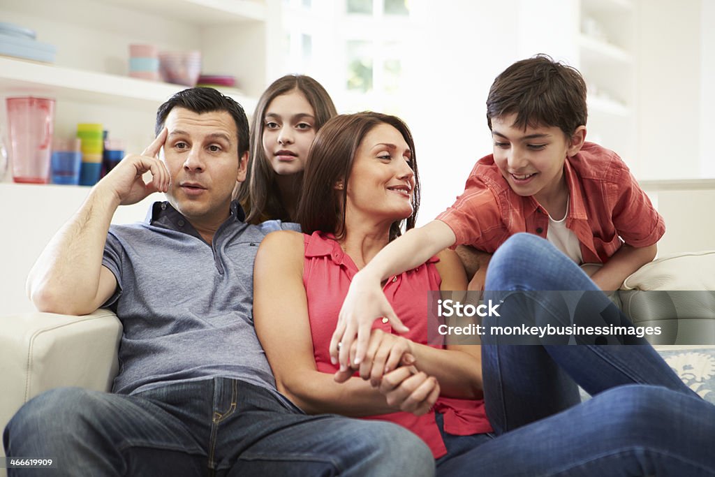 Латиноамериканская семья, сидящая на диване смотреть телевизор вместе - Стоковые фото Картофельные чипсы роялти-фри