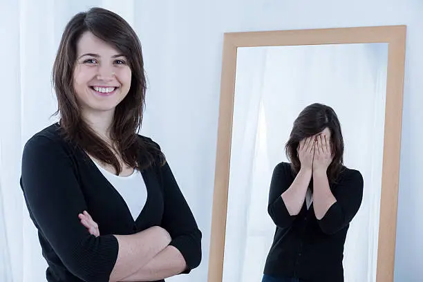 Photo of Woman smiling while reflection has hands over face 