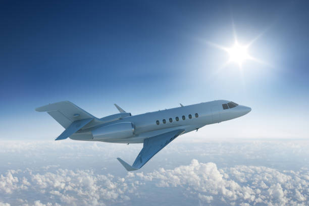 istock Private jet flying past the sun in blue sky. 466625668