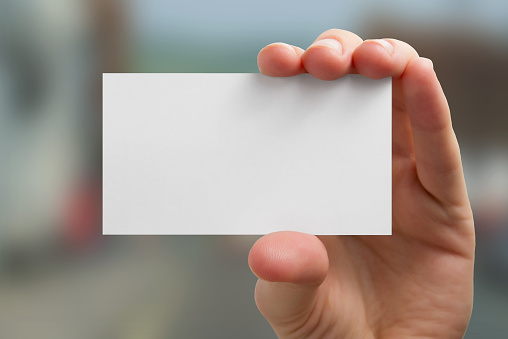 A hand holding a blank business card on blurred background