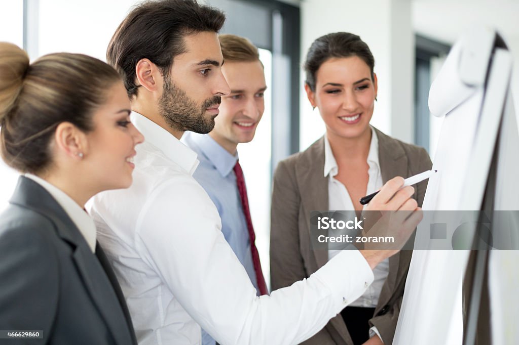 Working together Group of business people working together, drawing on flipchart Flipchart Stock Photo