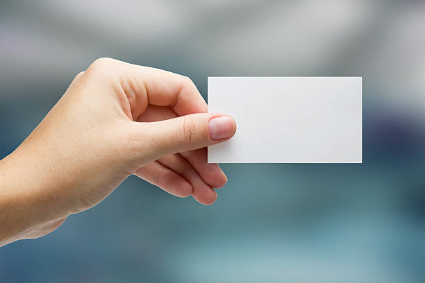 Hand holding white business card on blurred background