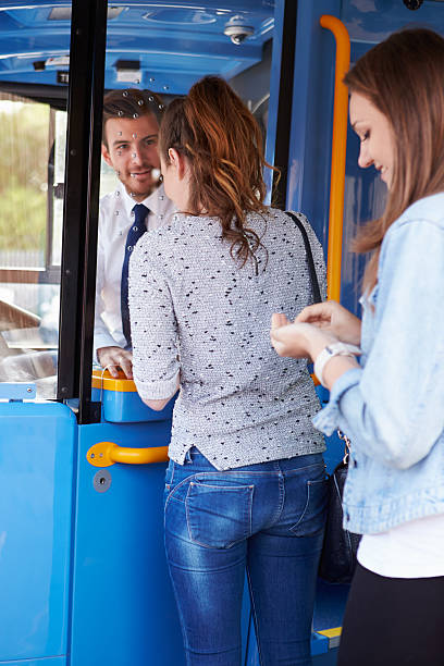 istock Two Young Women Boarding Bus And Buying Ticket 466632349
