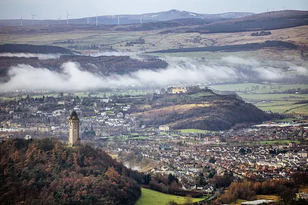 Looking down from the Ochil Hills into Glen Devon, Scotl and to the National Wallace Monument on Abbey Craig on a foggy morning, Beyond is the city of Stirling and on the volcanic hill above the city is the medieval Stirling Castle.