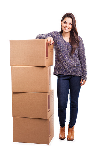 Cheerful and attractive young brunette leaning of a pile of boxes ready for shipping