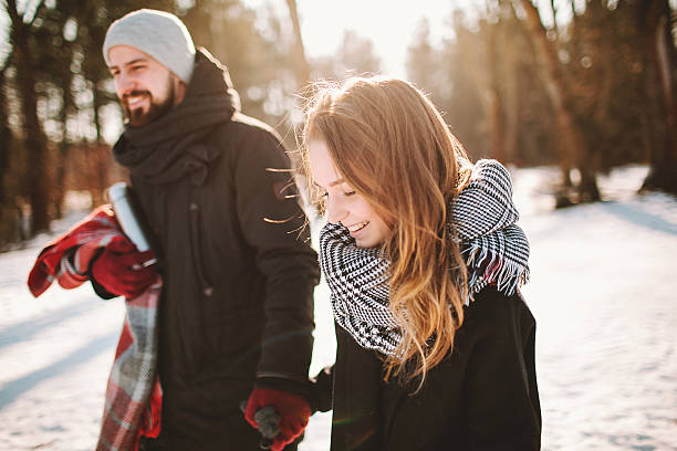 Young hipster couple walking in winter forest holding hands stock photo