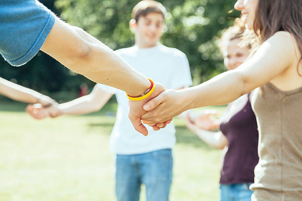 istock Teens forming circle holding hands outside on green grass 466638090