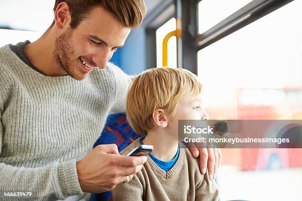 Father Using Mobile Phone On Bus Journey With Son Stock Photo - Download Image Now - Bus, Child, Parent