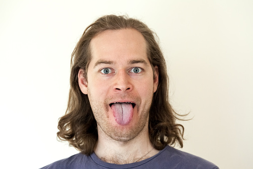 Man sticking out  tongue, close-up, isolated on gray