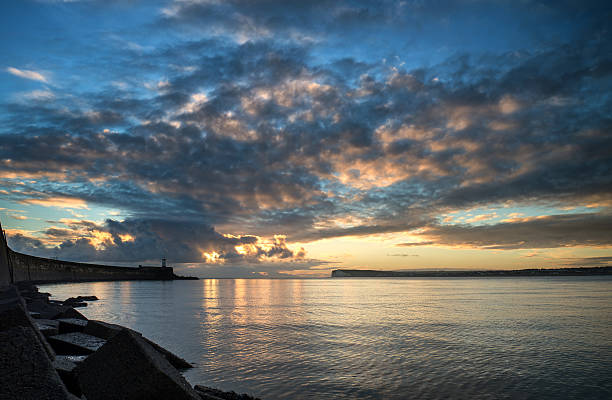 istock Beautiful vibrant sunrise sky over calm ocean with lighthouse 466644395
