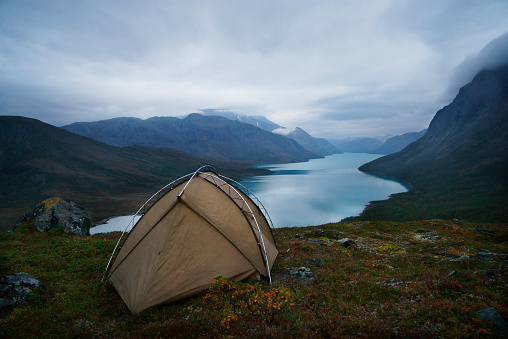 Single tent in front of a scenic view at lake Gjende and a remote mountain range in the Jotunheimen national park, Norway. Overcast at dawn. Nobody. XXXL (Sony Alpha 7R)