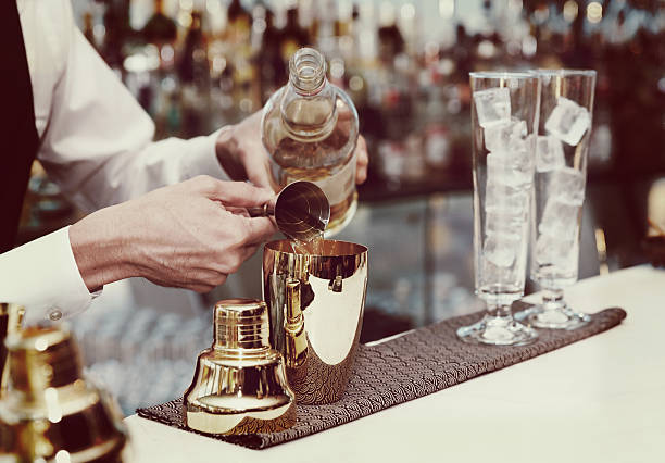Bartender is making a cocktail, toned Bartender is pouring liquor in golden shaker, toned image cocktail shaker photos stock pictures, royalty-free photos & images
