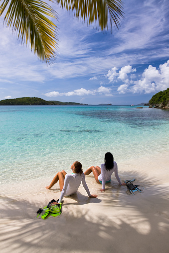 two young women sunbathing and relaxing on a beach after snorkeling in St.John, US Virgin Islands