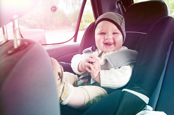 Happy boy is secure in a baby car seat Portrait of a cute and happy boy who smiles at the camera. He sits in a baby car seat and wears a seat belt., window seat vehicle stock pictures, royalty-free photos & images