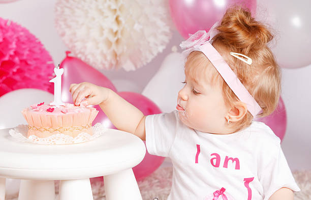 Cute baby girl tasting the birthday cake with fingers