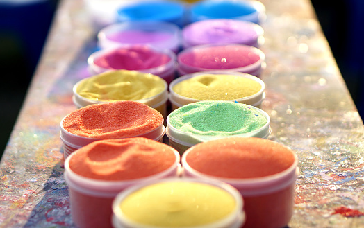 Multi-colored sand in plastic cans. Used for handicraft training for children.