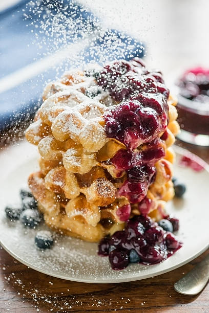 Stack of Belgium Waffles, Fresh Blueberries, Blueberry Compote, Icing Sugar.jpg A sprinkling of powdered sugar is added as a final touch on a stack of Belgium waffles with blueberry compote, fresh blueberries. sprinkling powdered sugar stock pictures, royalty-free photos & images