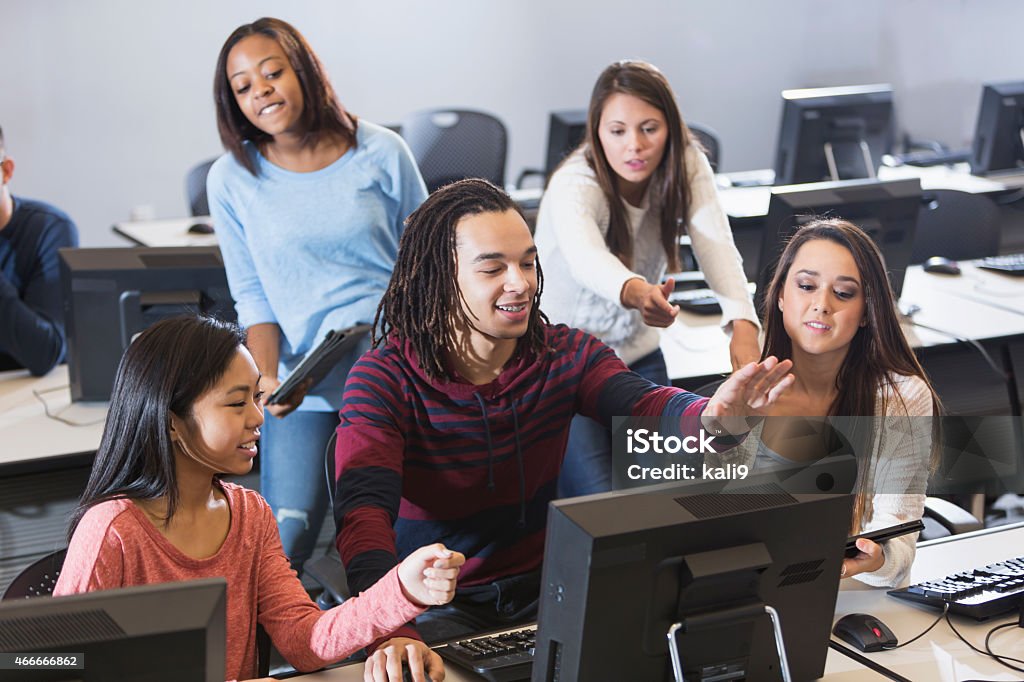 Students using computers A multiracial group of students using computers in a library or classroom.  The focus is on the people in the foreground. 16-17 Years Stock Photo