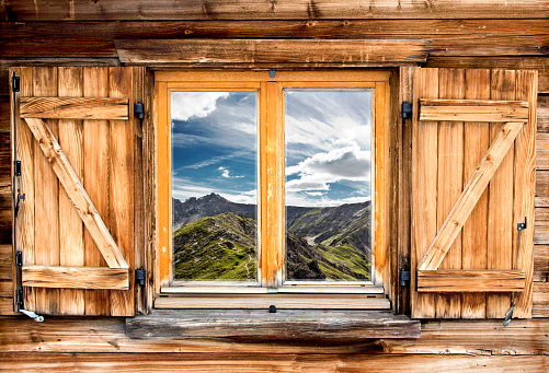 Weathered facade of a mountain hut with summer mountain reflections