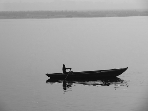 A Male canoeing in the lake with view of green forest in Nordland county, Northern Norway