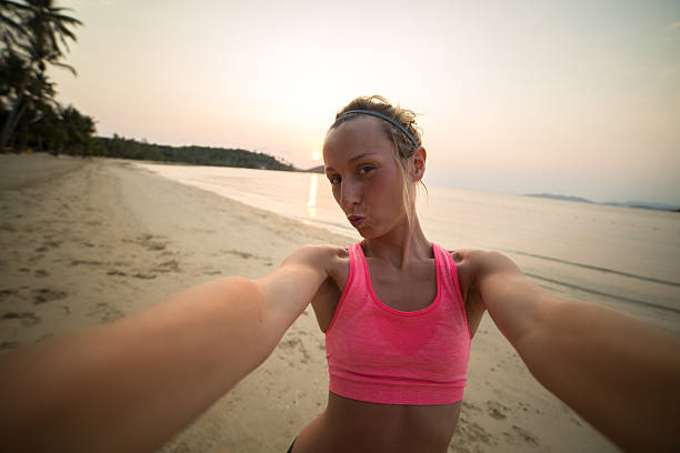 istock Young woman on beach taking selfie after workout 466675882