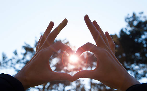 istock Beautiful female palms depict heart with sun rays bokeh 466676552