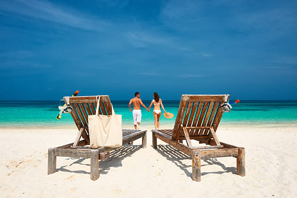 coppia in bianco in esecuzione su una spiaggia alle maldive - chair beach chaise longue isolated foto e immagini stock