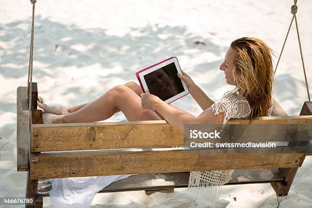 Woman On Bench On Tropical Beach Using Digital Tablet Stock Photo - Download Image Now