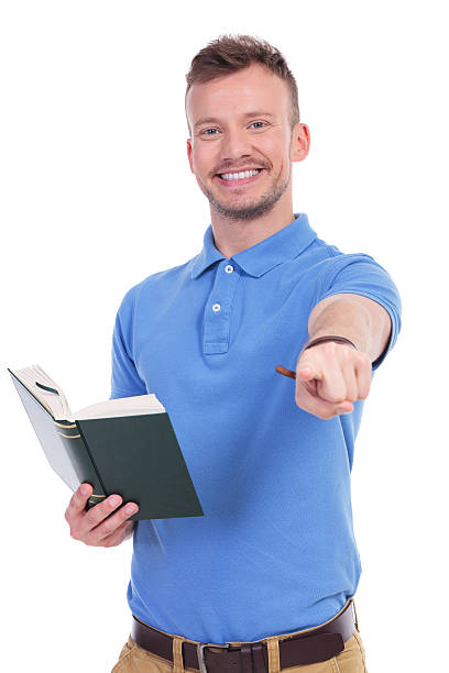 istock young casual man with book points at you 466676916