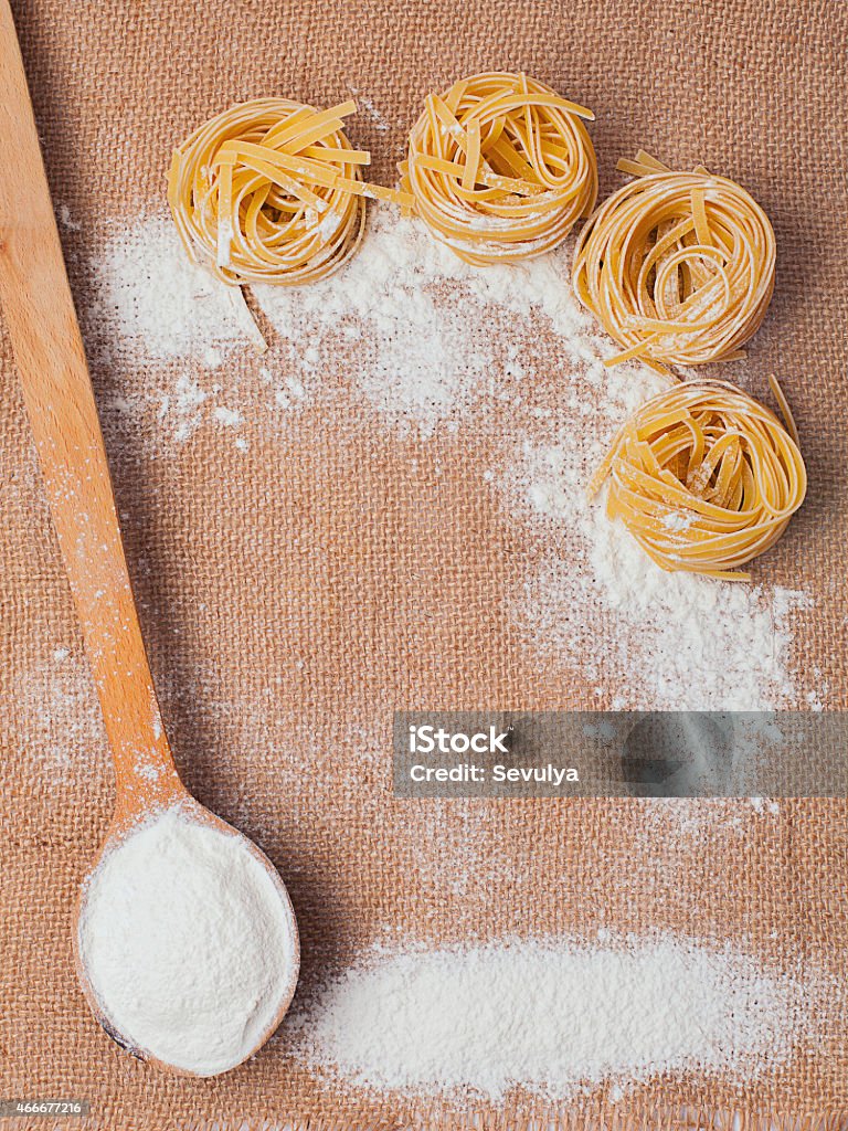 Pasta and wooden spoon with flour on sacking 2015 Stock Photo