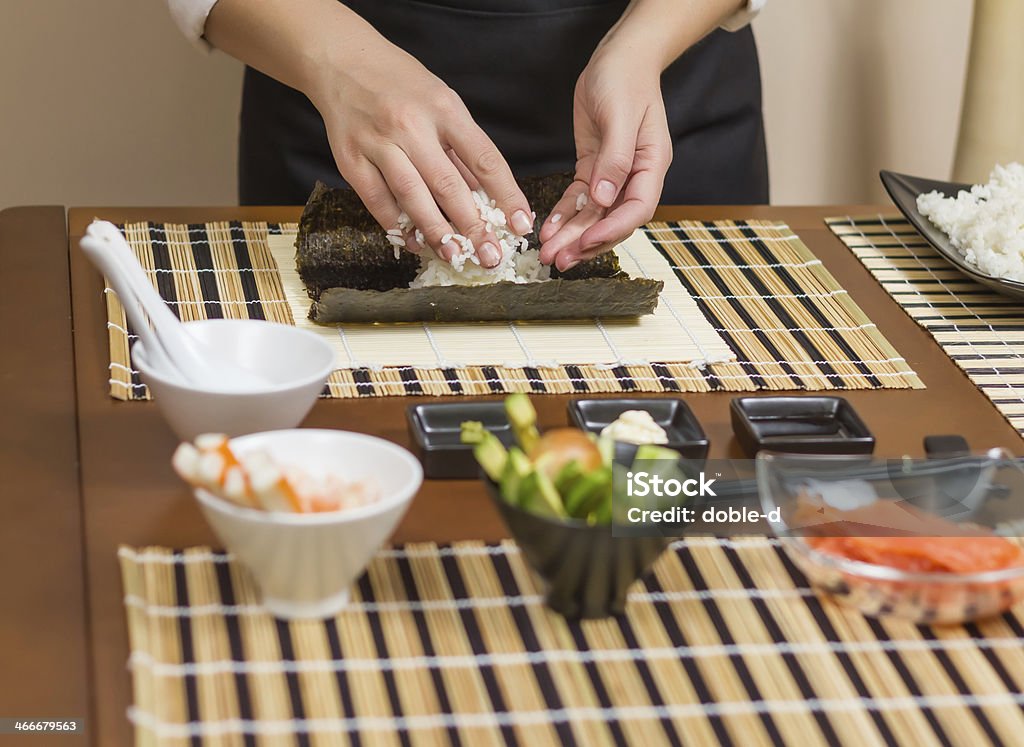 Woman chef filling japanese sushi rolls with rice Hands of woman chef filling japanese sushi rolls with rice on a nori seaweed sheet Adult Stock Photo