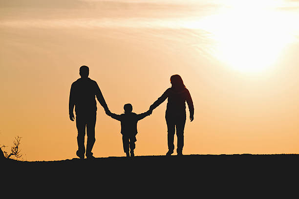 istock Two parents and a child silhouetted on a sunset 466683527