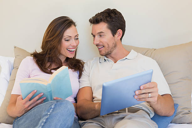 istock Happy couple with laptop and book on couch 466684340